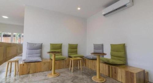 a room with a bench with green cushions and tables at Maximize Brand New Hostel Udonthani in Udon Thani