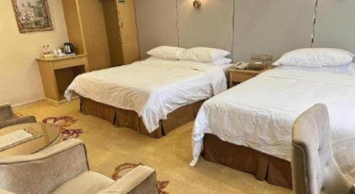a hotel room with two beds and a chair at Vienna 3 Best Shanghai Baoshan Fengxiang Road in Shanghai