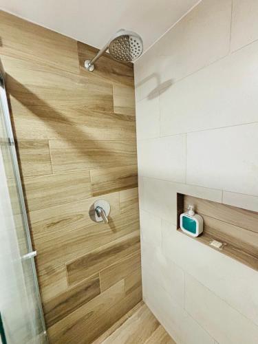 a bathroom with a shower with a wooden wall at Depa Familiar con cochera 6 min Centro Médico y Catedral in Guadalajara