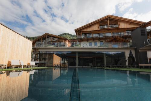 a house with a swimming pool in front of a building at Almfamilyhotel Scherer in Obertilliach
