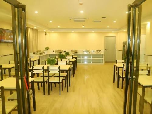 a restaurant with tables and chairs and a kitchen at GreenTree Inn Yichun Mingyueshan Airport in Yichun