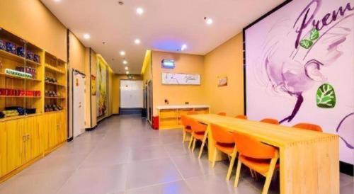 a restaurant with a long table and orange chairs at 7 Days Premium·Shihezi Passenger Terminal in Shihezi