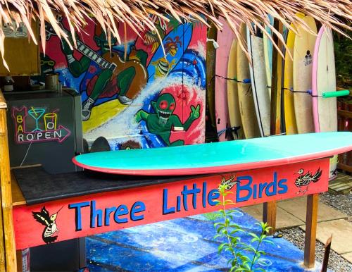 a three little birds surfboard on a stand next to surfboards at Three Little Birds Surf Hostel in General Luna