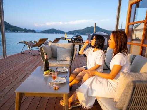 two women sitting on the deck of a boat at 瀬戸内隠れ家リゾート in Onomichi