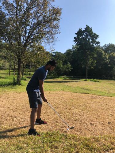 a man is playing golf in a field at Ahaspokuna by Eco Team in Belihul Oya