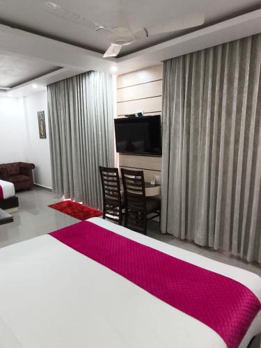 a bedroom with a large bed and a television at Aliza Inn And Suites By SRS Hotels in Dharamshala