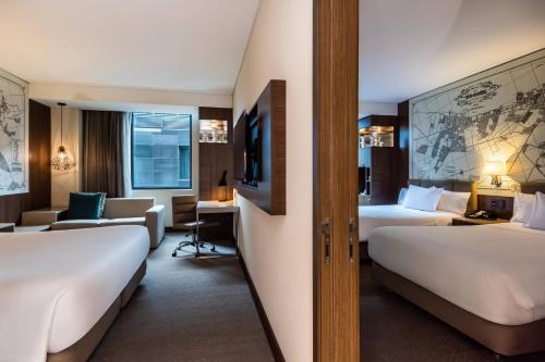 a hotel room with two beds and a desk at Courtyard by Marriott Bogota Airport in Bogotá