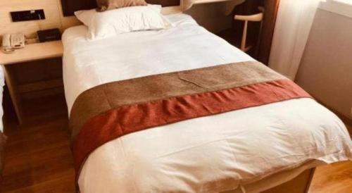 a large bed in a room with a desk at Jun Hotel Jiangsu Nanjing Gulou District Gupinggang in Nanjing