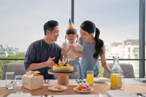 a family blowing out candles on a birthday cake at Sheraton Hai Phong in Hai Phong