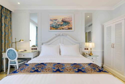 a bedroom with a white bed with a desk and a bed sidx sidx at Lan Rung Beach Resort in Long Hai