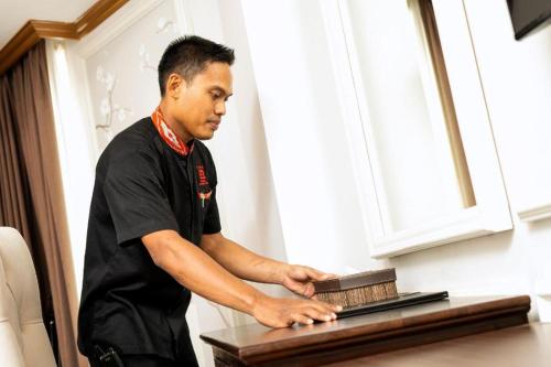 a man standing next to a table with a laptop at Hotel Pangeran in Pekanbaru