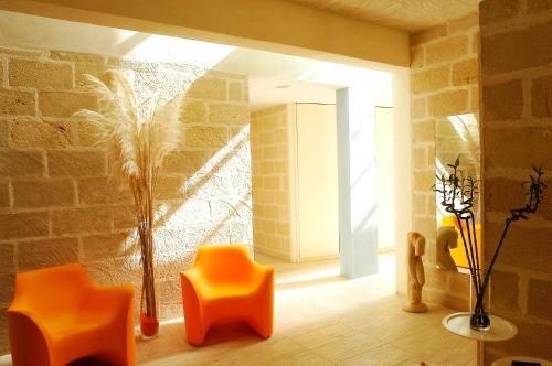 a room with orange chairs and a brick wall at Cave Bianche Hotel in Favignana