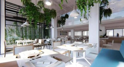 a restaurant with white tables and chairs and plants at Thaisun Bangkok Hotel in Bangkok