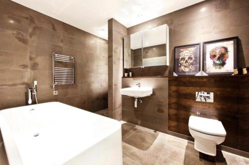 a bathroom with a tub and a toilet and a sink at Nest Penthouse in London