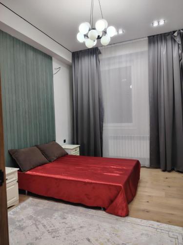 - une chambre avec un lit rouge et un lustre dans l'établissement 24 home Aktau, à Aktau