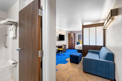 a hotel room with a blue couch and a desk at Microtel Inn & Suites By Wyndham Conway in Conway