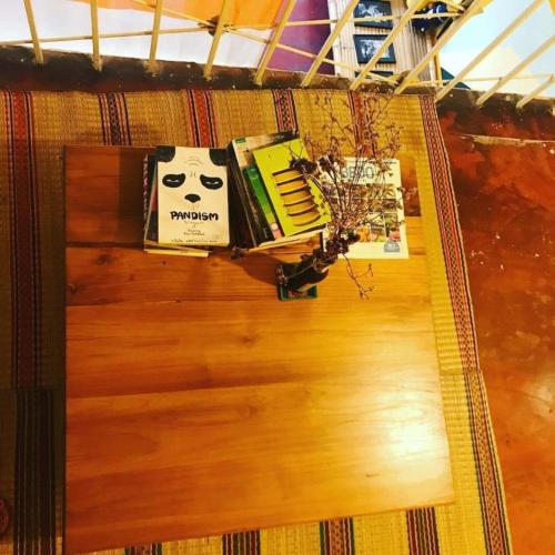 a table with books on top of a wooden floor at Oldie and Sleepy Hostel in Udon Thani