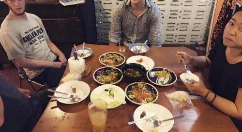 a group of people sitting around a table with food at Oldie and Sleepy Hostel in Udon Thani