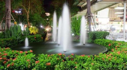 a fountain in the middle of a garden with flowers at Oldie and Sleepy Hostel in Udon Thani