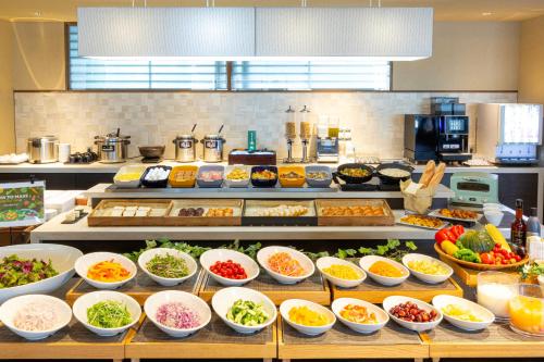 a buffet line with many bowls of different types of food at Hotel Keihan Kyoto Hachijoguchi in Kyoto