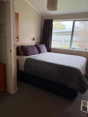a bedroom with a bed with purple pillows and a window at Bed and Breakfast Happy Home Taupo Accommodation in Taupo