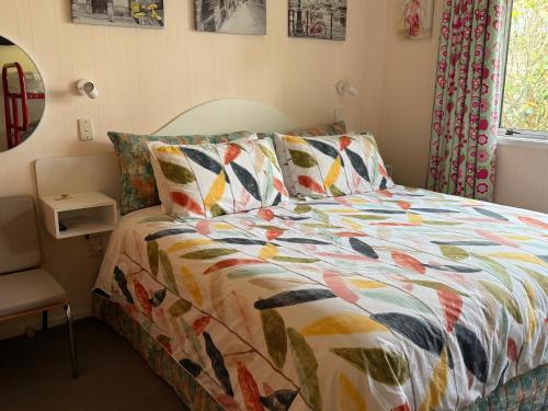 a bed with a colorful comforter in a bedroom at Bed and Breakfast Happy Home Taupo Accommodation in Taupo
