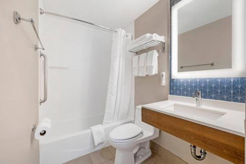 a bathroom with a sink and a toilet and a mirror at Country Inn & Suites by Radisson, Staten Island in Staten Island