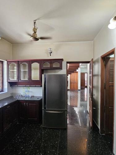 a kitchen with a stainless steel refrigerator and wooden cabinets at Vipanchika Home Stay in Trivandrum
