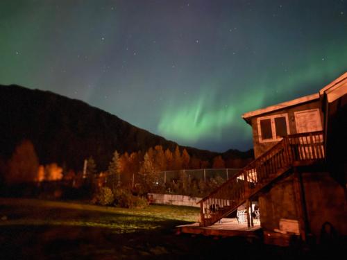 a house with a deck and the aurora in the sky at Bear Mountain View 4BR Home- Only 25 Min from Anchorage, Great Central location ,- 5 star property in Eagle River