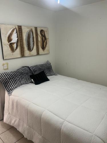 a white bed in a room with two paintings on the wall at Mini loft nogales in Heroica Nogales