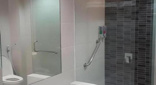 a bathroom with a glass shower with a toilet at Kharisma Hotel in Madiun