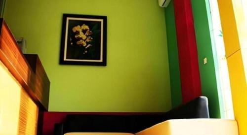 a green wall with a painting of flowers on it at Pineapple Mansion in Solo