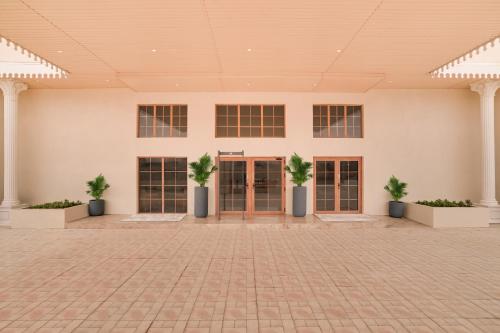 a large white building with doors and potted plants at Lemon Tree Hotel Morbi 
