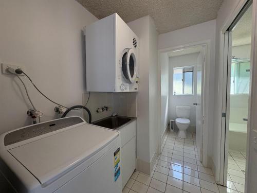 a small white kitchen with a sink and a toilet at Spinnaker Seas Unit 8 in Caloundra