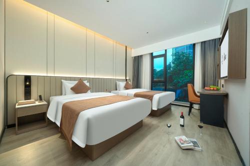 a hotel room with two beds and a desk at Rezen Borui Hotel Guangzhou Tower Sun Yat-sen University Branch in Guangzhou