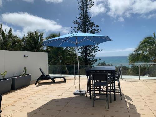 a patio with a table and chairs and an umbrella at 'Jemingar's Place' 207 - Rainbow Beach in Rainbow Beach