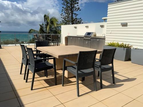 a wooden table and chairs on a patio with the ocean at 'Jemingar's Place' 207 - Rainbow Beach in Rainbow Beach