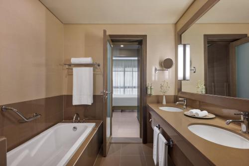 a bathroom with two sinks and a bath tub at Park Arjaan by Rotana, Abu Dhabi in Abu Dhabi