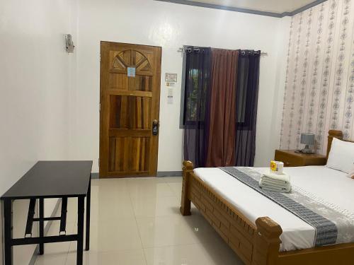 a bedroom with a bed and a table and a door at ELEN INN - Malapascua Island Air-conditioned Room1 in Malapascua Island
