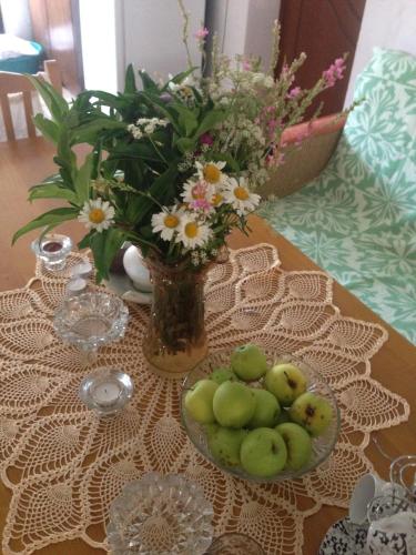 a table with a vase of flowers and a bowl of fruit at Eco Garten Guest House in Shkodër