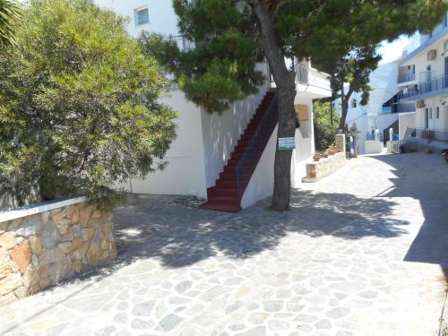 a tree sitting next to a building with a staircase at Pension Galazios Kolpos in Patitiri
