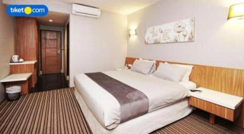 a hotel room with a large bed and a desk at Kenari Tower Hotel in Makassar
