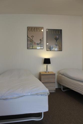 a bedroom with two beds and a nightstand and two posters at Odense Apartments in Odense