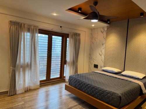 a bedroom with a bed and a ceiling fan at Suvarna Millennium Suits in Mysore
