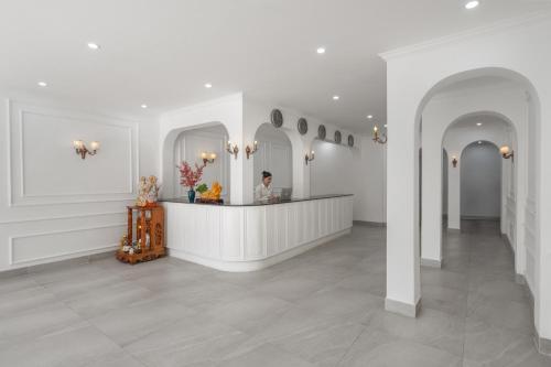 a man standing at a counter in a white room at Golden Glow Hue City in Hue