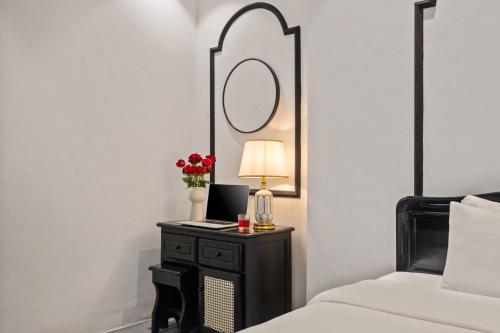 a bedroom with a table with a lamp and a mirror at Golden Glow Hue City in Hue