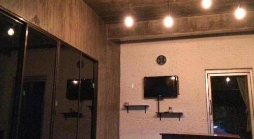 a room with a wall with a tv and a mirror at Rim Kaeng resort in Phetchaburi