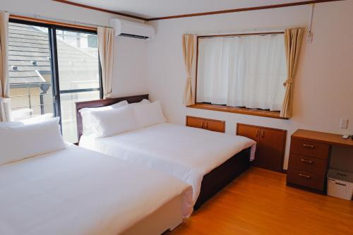two beds in a small room with a window at Akira Hiro House - Room201 in Tokyo