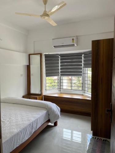 a bedroom with a bed and a window with blinds at Enhance Lifestyle Service Apartments in Thamarassery