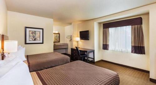 a hotel room with two beds and a desk at Lemon Heights Inn in Tustin